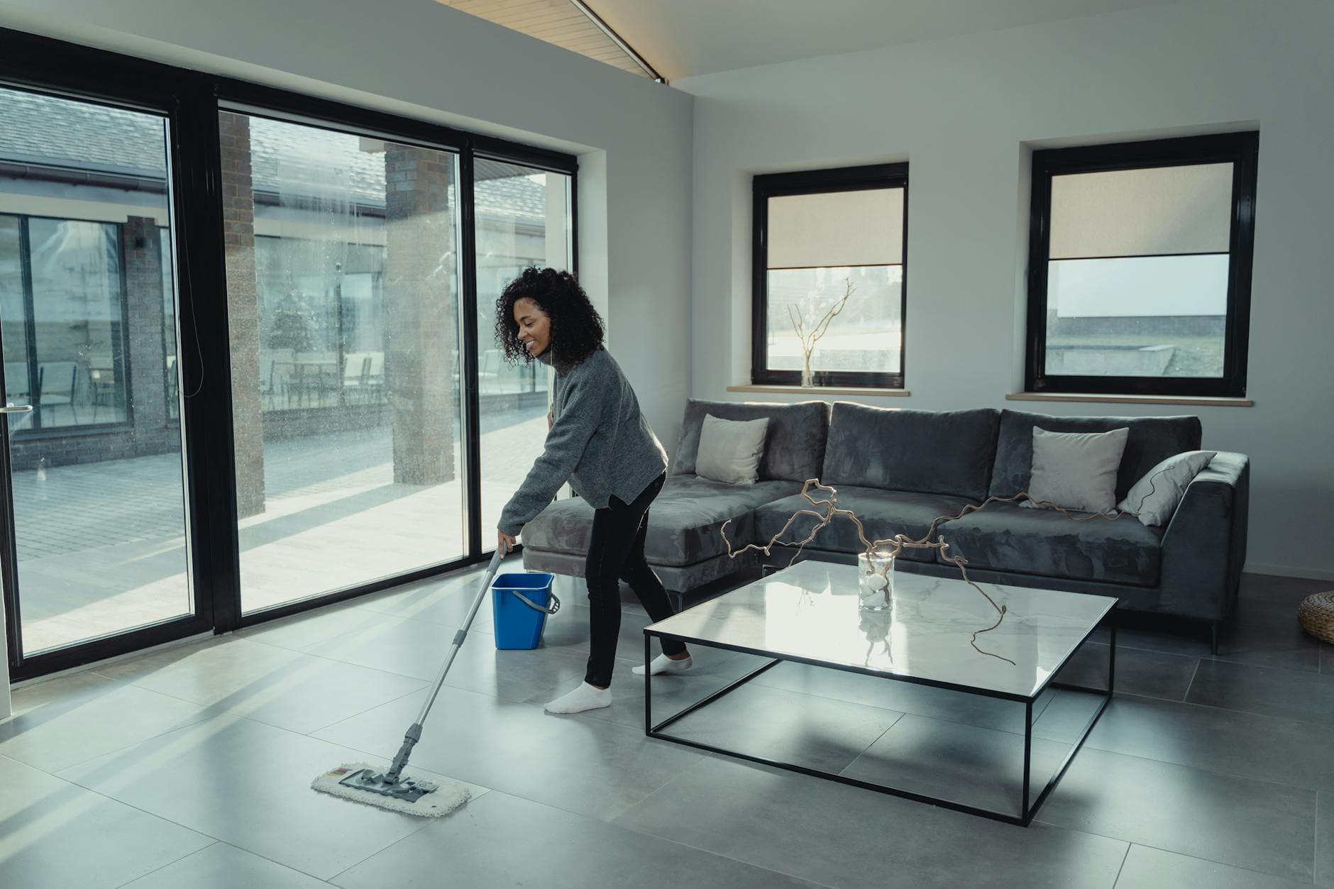 House cleaner mopping a bright, modern Westchester apartment with large windows — Monthly Cleaning in Westchester and the Hudson Valley
