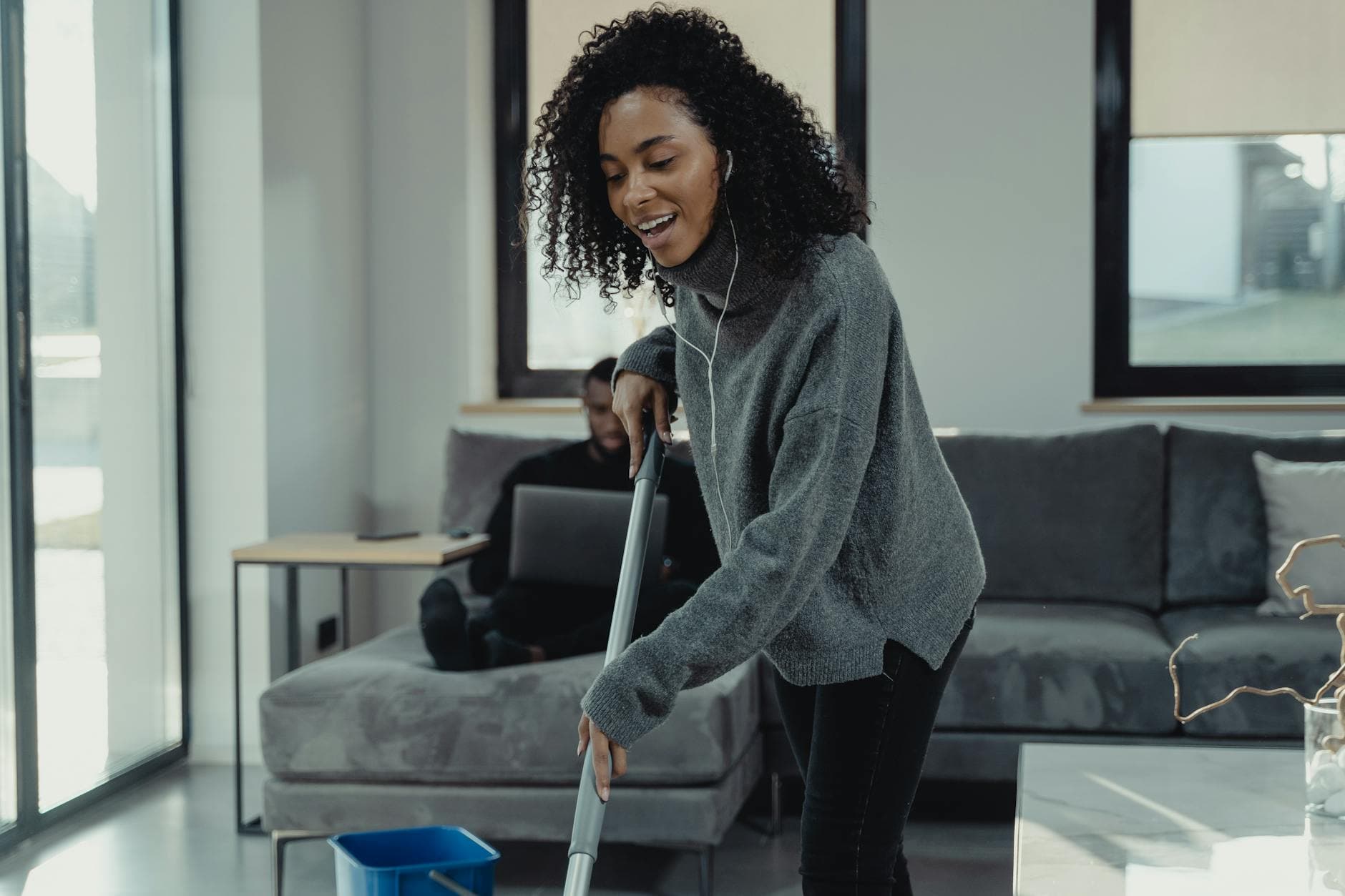 A professional house cleaner mopping the floor of a cozy Westchester living room — Weekly Maid Service in Yonkers, Westchester County