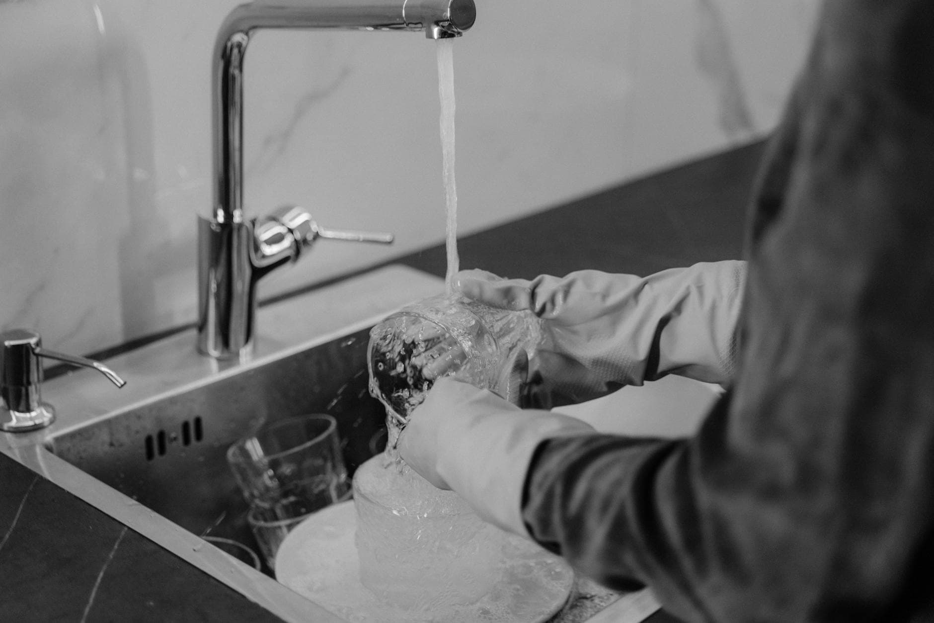 Westchester kitchen cleaning service washing dishes under running water at the sink — Deep Cleaning in New Rochelle, Westchester County